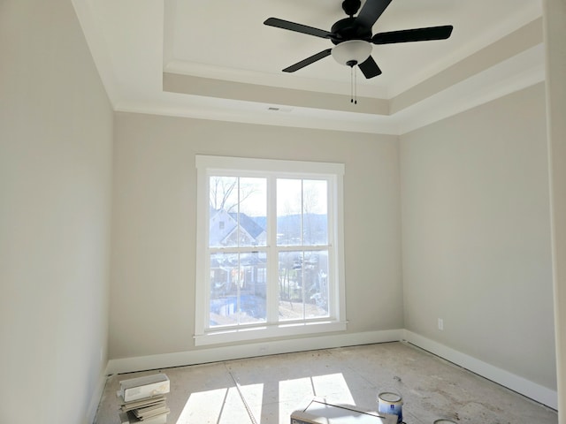 empty room with a raised ceiling, ornamental molding, and ceiling fan