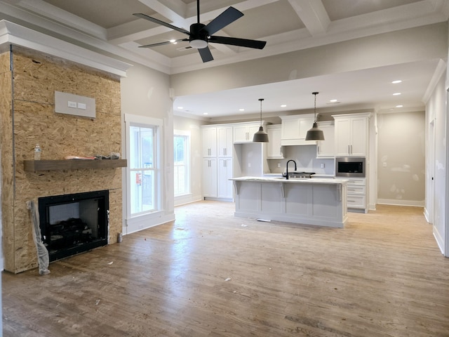 kitchen with a large fireplace, light hardwood / wood-style flooring, hanging light fixtures, and white cabinets