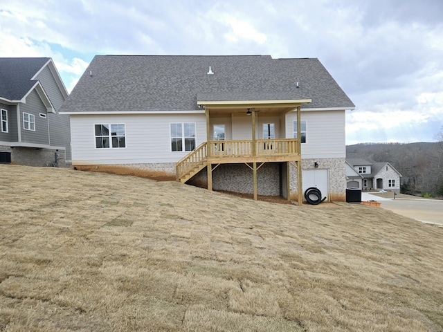 back of property featuring central AC, a wooden deck, and a lawn