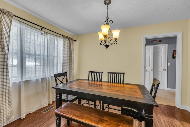 dining room with hardwood / wood-style floors, a notable chandelier, and a textured ceiling