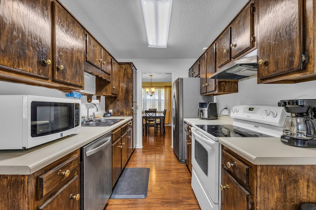 kitchen featuring a textured ceiling, white appliances, dark brown cabinets, wood-type flooring, and sink