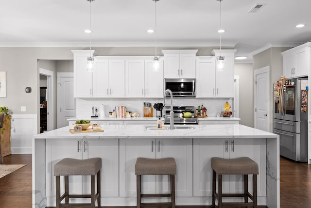 kitchen featuring hanging light fixtures, stainless steel appliances, and a kitchen island with sink