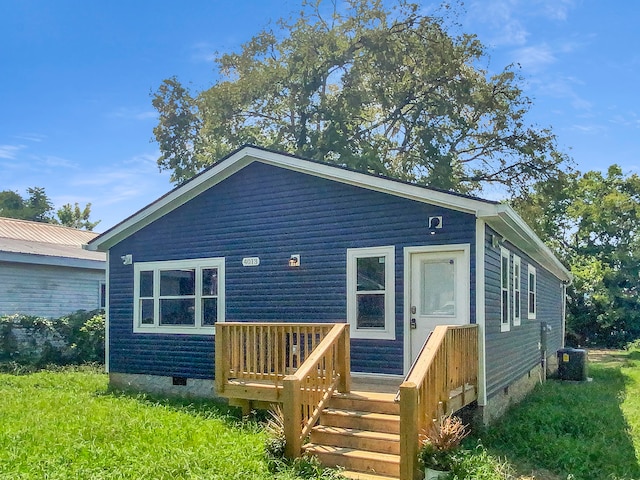 rear view of house featuring central AC unit and a lawn