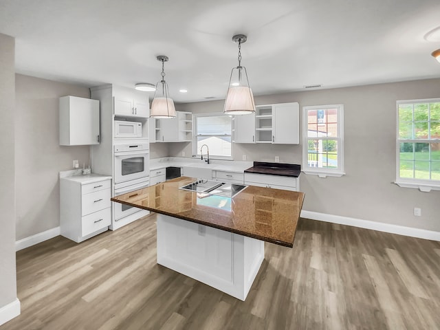 kitchen featuring a kitchen island, hardwood / wood-style floors, white appliances, and white cabinets