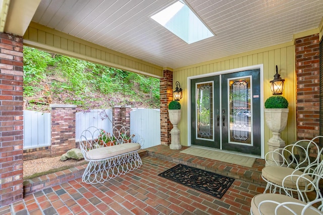 entrance to property with brick siding, a patio area, and french doors
