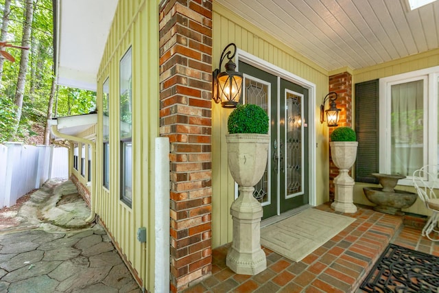 entrance to property with covered porch and brick siding