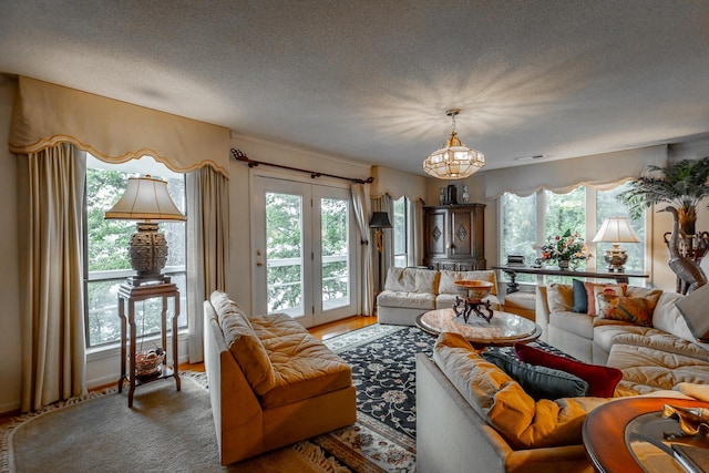 living area with a textured ceiling, visible vents, wood finished floors, and an inviting chandelier