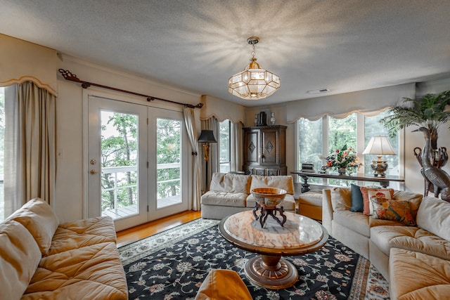 living room featuring hardwood / wood-style floors, plenty of natural light, an inviting chandelier, and a textured ceiling