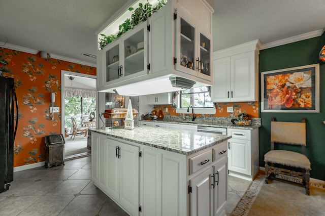 kitchen featuring black refrigerator, ornamental molding, and white cabinetry