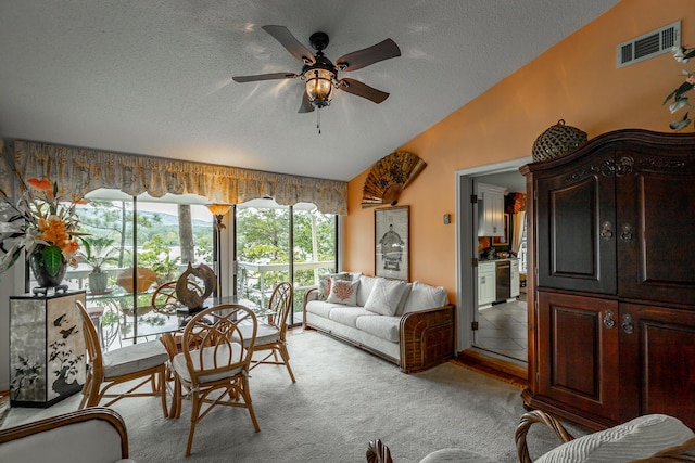 living room featuring carpet flooring, a ceiling fan, a textured ceiling, lofted ceiling, and visible vents
