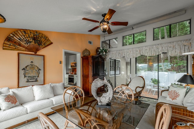 living room with a textured ceiling, ceiling fan, and vaulted ceiling