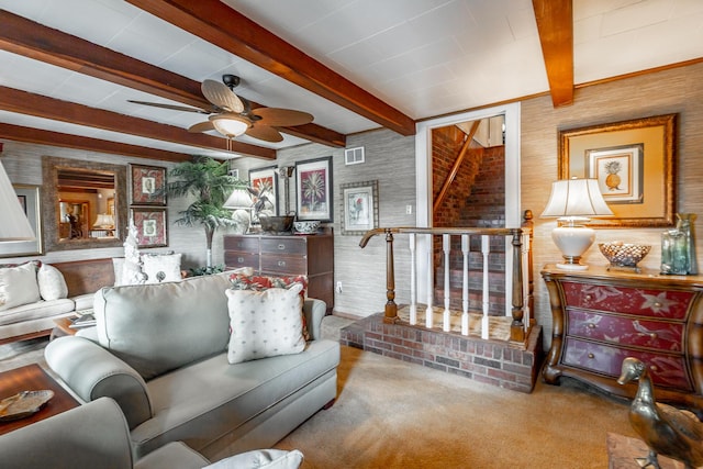 carpeted living room with a ceiling fan, beam ceiling, stairs, and visible vents