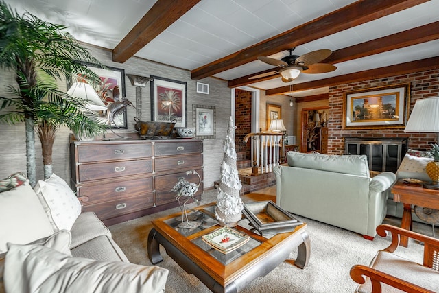 carpeted living area with brick wall, beamed ceiling, visible vents, a ceiling fan, and a fireplace