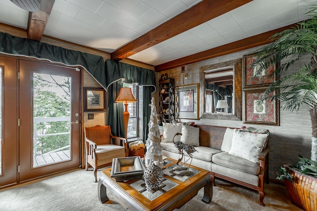 carpeted living area with beam ceiling