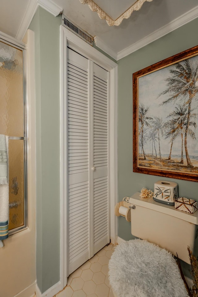 full bathroom featuring a stall shower, crown molding, toilet, and tile patterned flooring