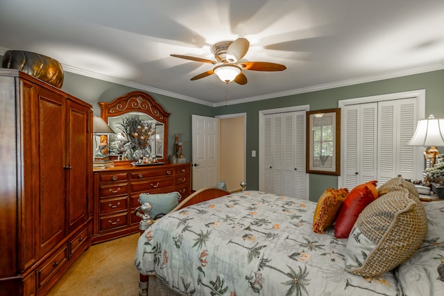 carpeted bedroom with crown molding, ceiling fan, and two closets