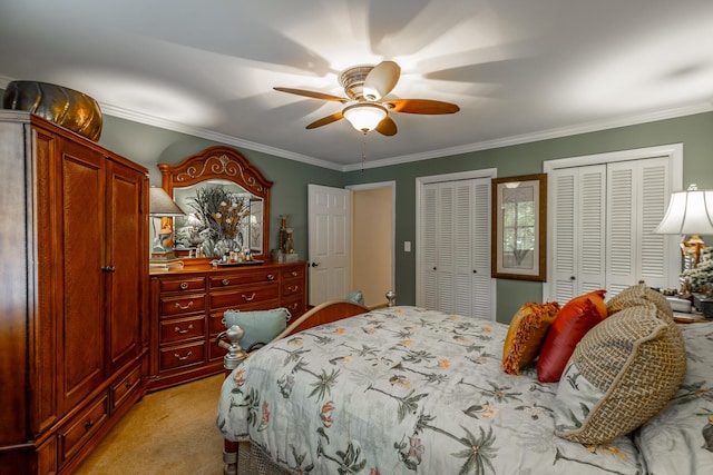 bedroom with ornamental molding, a ceiling fan, light carpet, and two closets