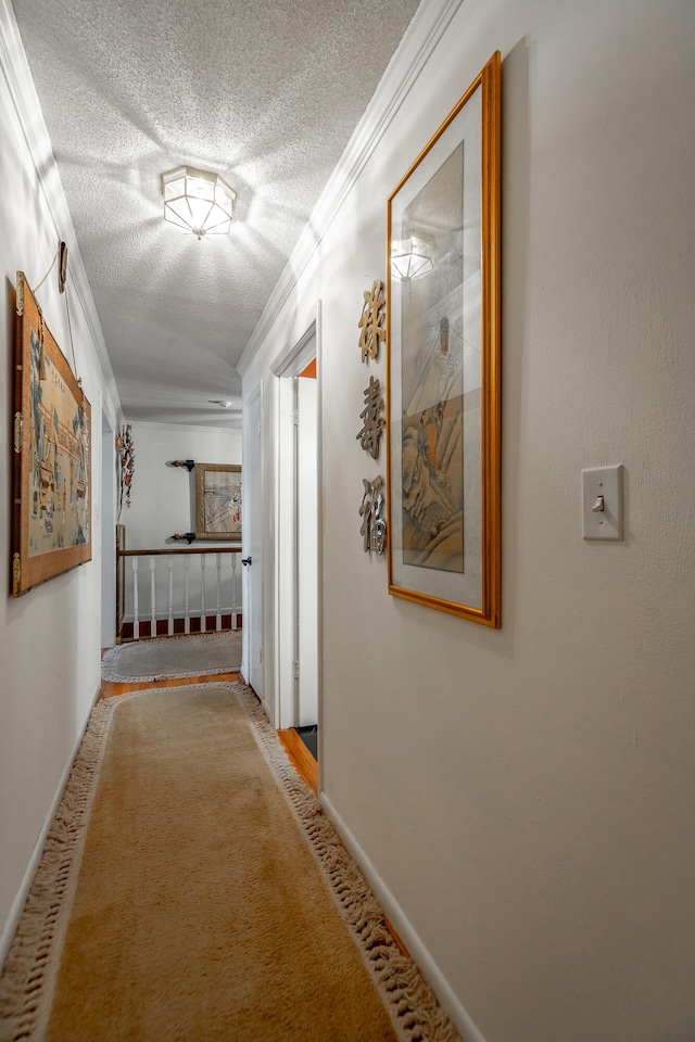 corridor with ornamental molding, a textured ceiling, and carpet