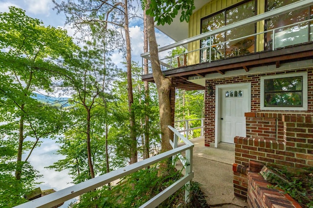 property entrance with brick siding and a balcony