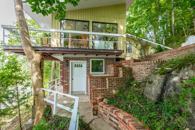 property entrance with a balcony and brick siding