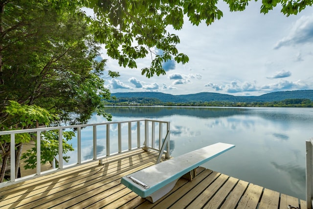 view of dock with a water and mountain view and a balcony