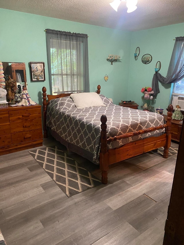 bedroom featuring ceiling fan, hardwood / wood-style flooring, and a textured ceiling