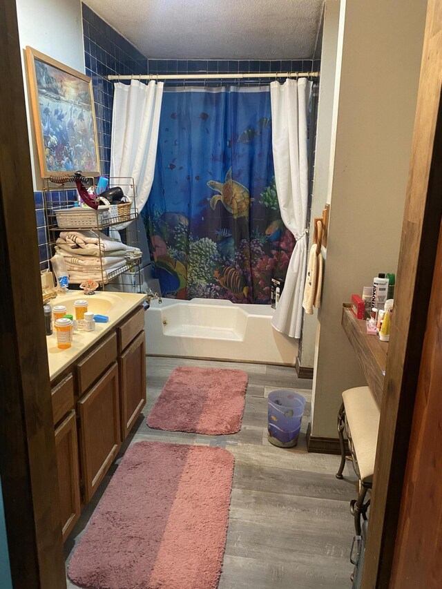 bathroom with shower / bath combo with shower curtain, hardwood / wood-style flooring, a textured ceiling, and vanity