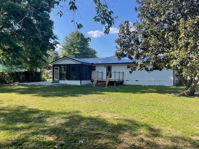 back of property with a sunroom, a yard, and a wooden deck