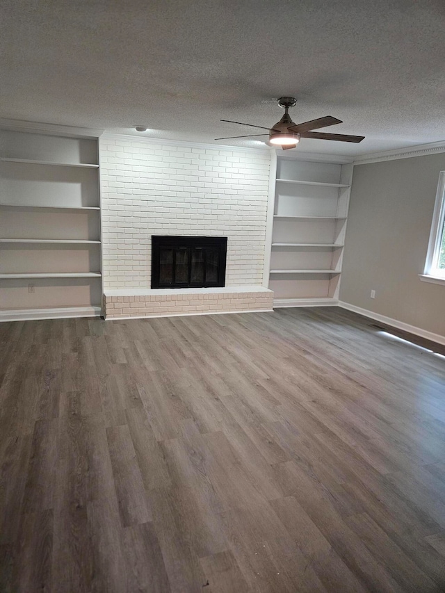 unfurnished living room featuring dark wood-type flooring, a textured ceiling, a brick fireplace, and ceiling fan