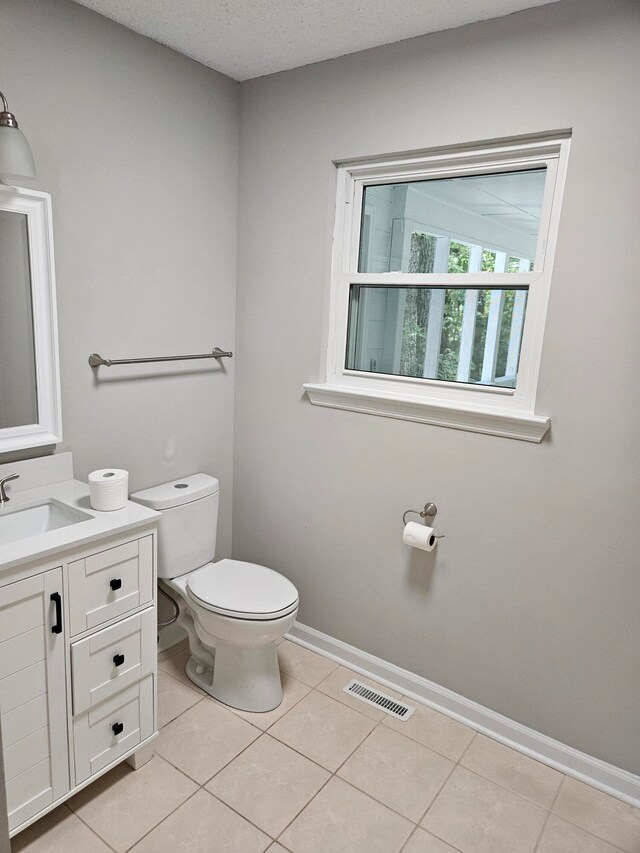 bathroom featuring tile patterned flooring, toilet, a textured ceiling, and vanity