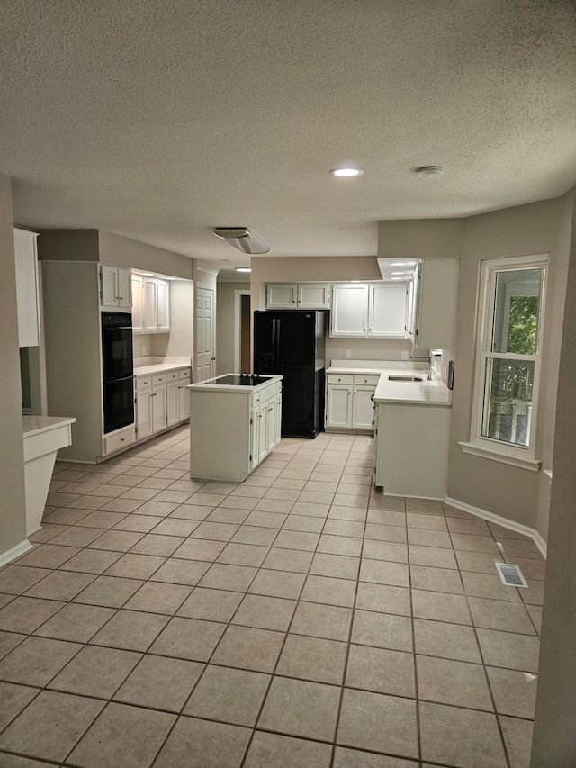 kitchen with white cabinetry, a textured ceiling, light tile patterned floors, black appliances, and a center island