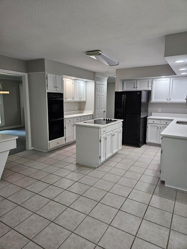 kitchen with black appliances, a kitchen island, a textured ceiling, and white cabinets