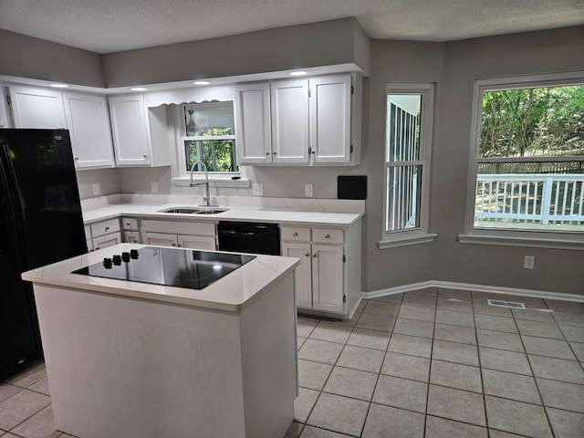 kitchen with a textured ceiling, black appliances, sink, white cabinetry, and light tile patterned flooring