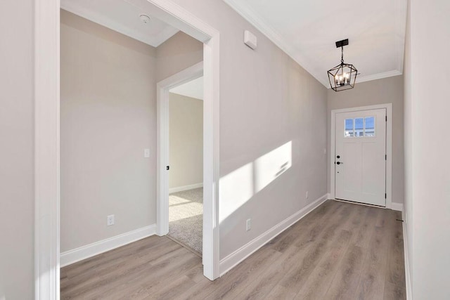 foyer entrance featuring ornamental molding, an inviting chandelier, and light wood-type flooring