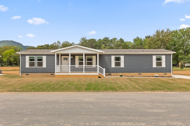 manufactured / mobile home with a mountain view, a front lawn, and a porch