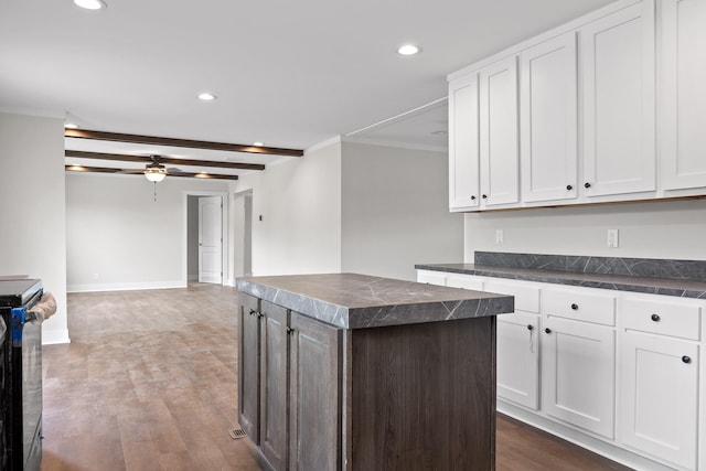 kitchen featuring a kitchen island, stainless steel electric stove, dark hardwood / wood-style floors, and white cabinets