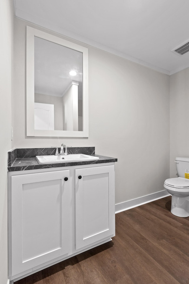 bathroom with ornamental molding, vanity, toilet, and hardwood / wood-style flooring