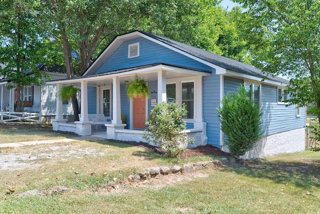 bungalow-style house featuring covered porch and a front yard