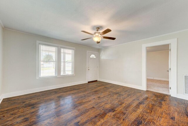 empty room with ornamental molding, dark wood-type flooring, and ceiling fan