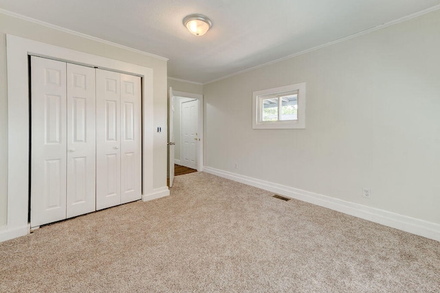 unfurnished bedroom featuring crown molding, light colored carpet, and a closet