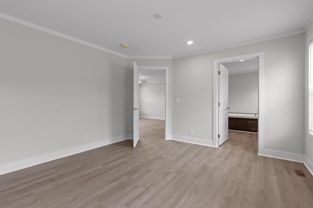 unfurnished bedroom featuring ensuite bath, crown molding, light hardwood / wood-style floors, and a spacious closet