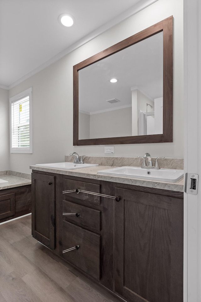 bathroom with ornamental molding, hardwood / wood-style floors, vanity, and a bathing tub