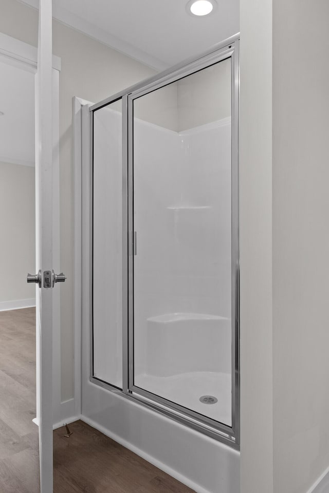 bathroom with wood-type flooring and a shower with shower door