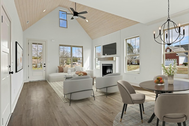 living area featuring wood finished floors, a fireplace, baseboards, and high vaulted ceiling