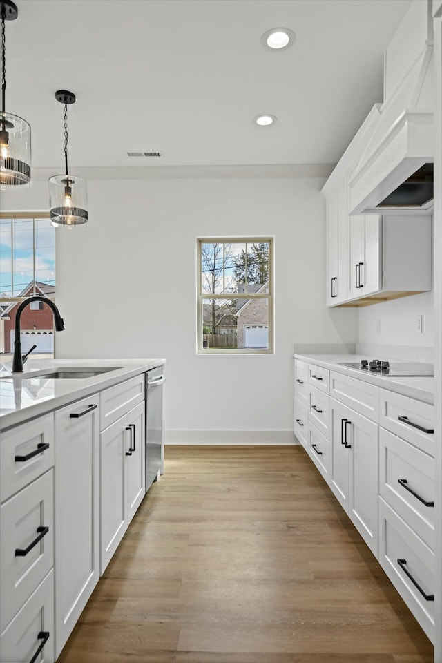 kitchen featuring visible vents, custom exhaust hood, a sink, light countertops, and black electric stovetop