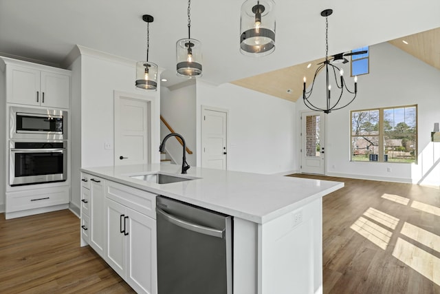 kitchen featuring a center island with sink, a sink, stainless steel appliances, light countertops, and open floor plan