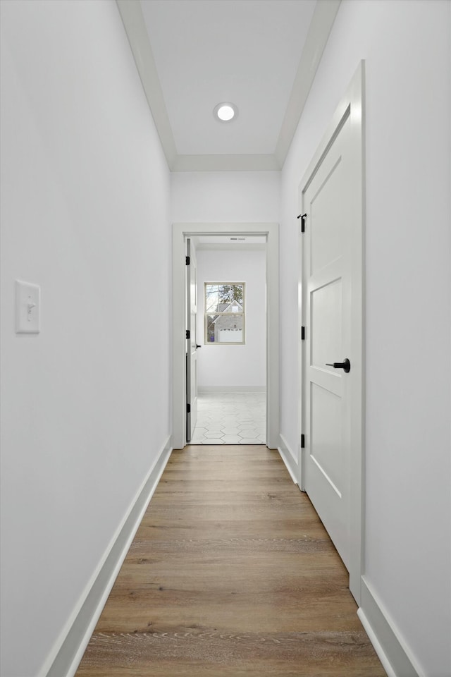 corridor with baseboards and wood finished floors