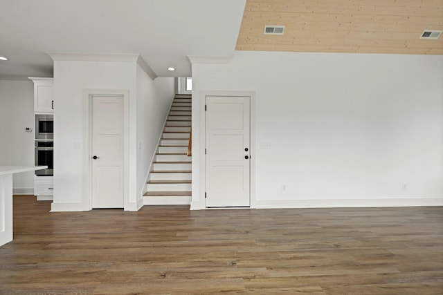 unfurnished room with visible vents, stairs, and wood finished floors