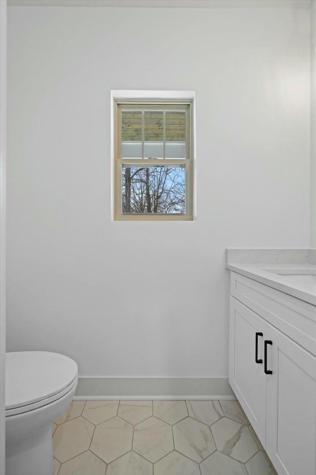 half bath with toilet, vanity, and baseboards