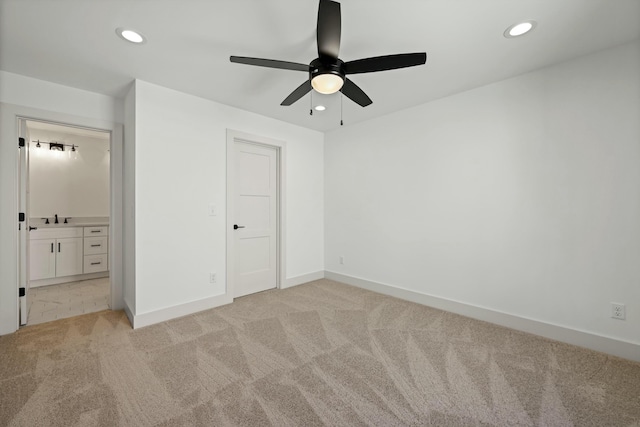 unfurnished bedroom with light carpet, recessed lighting, baseboards, and a sink